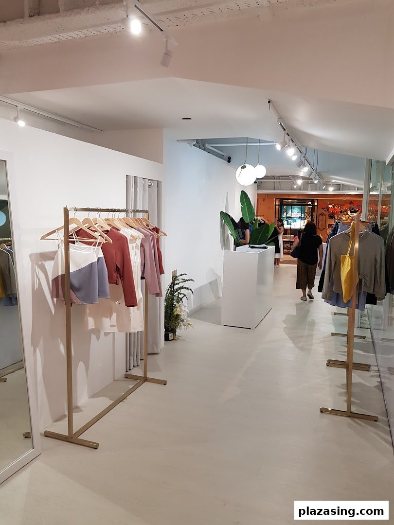 Interior view of a modern clothing boutique with apparel displayed on racks and a customer browsing.