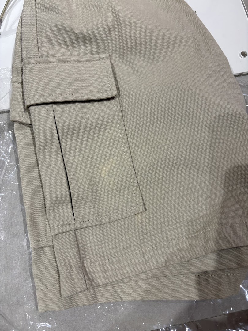 Close-up of beige cargo shorts or pants, showcasing fabric texture and pocket detail.
