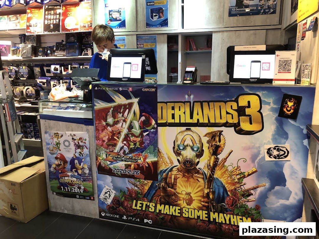 A staff member at the counter of GameMartz Plaza Sing, surrounded by popular game posters and merchandise.
