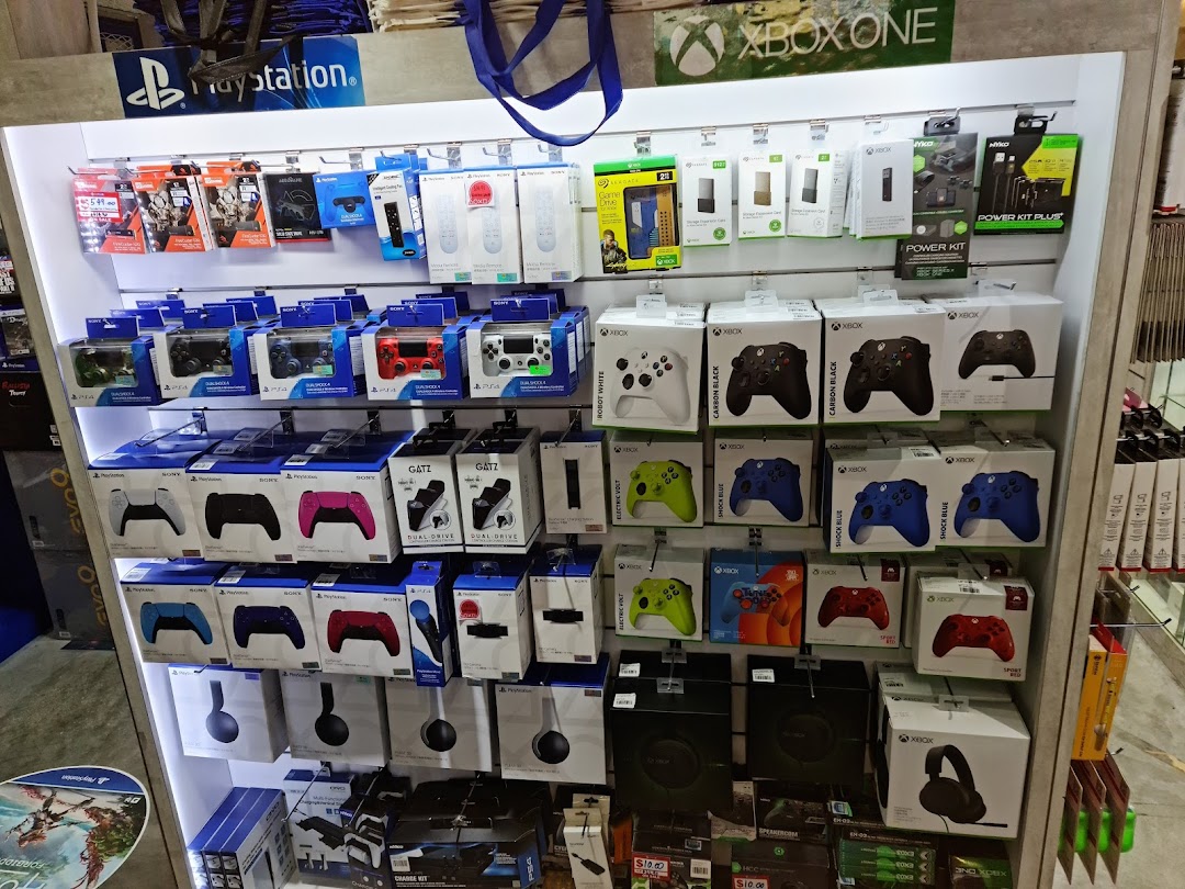 A vibrant display of PlayStation and Xbox gaming controllers, headsets, and accessories on shelves.