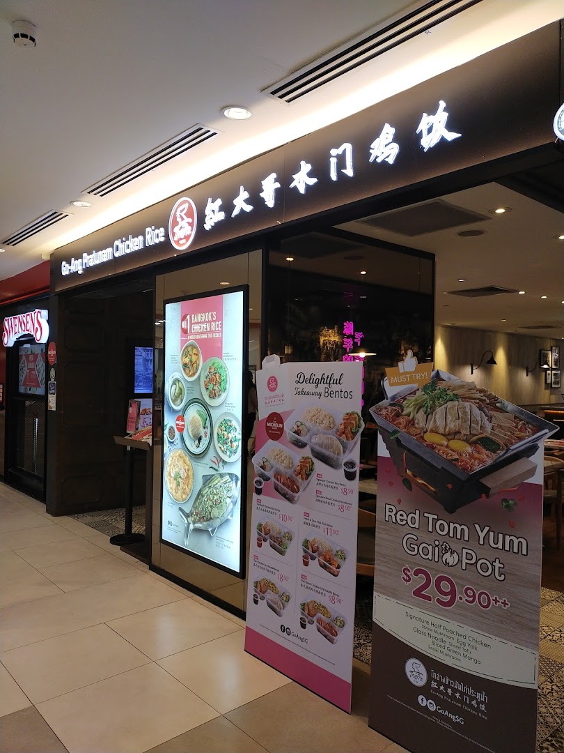 The storefront of Go-Ang Pratunam Chicken Rice, featuring its signage and promotional displays for bentos and hot pot.