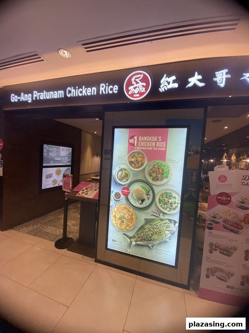 The illuminated entrance of Go-Ang Pratunam Chicken Rice, featuring a large digital display of their signature dishes.