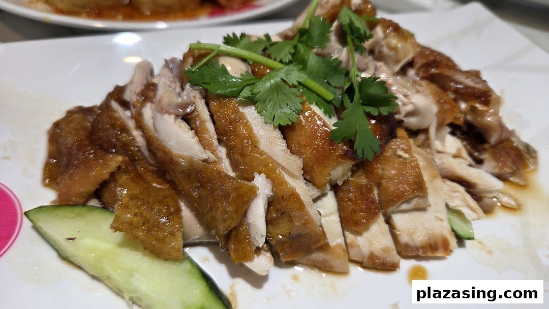 A close-up of succulent sliced roasted chicken with crispy skin, garnished with fresh cilantro and cucumber.