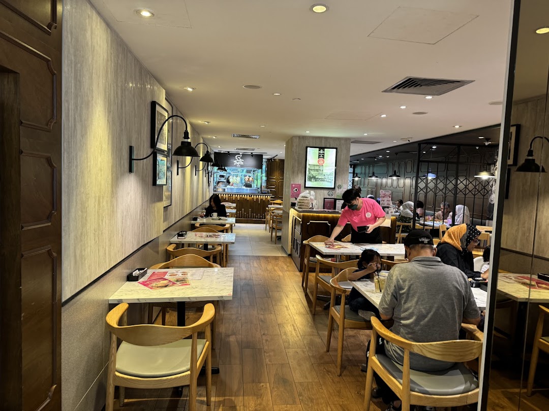 A view of the interior dining area at Go-Ang Pratunam Chicken Rice, with customers and staff present.