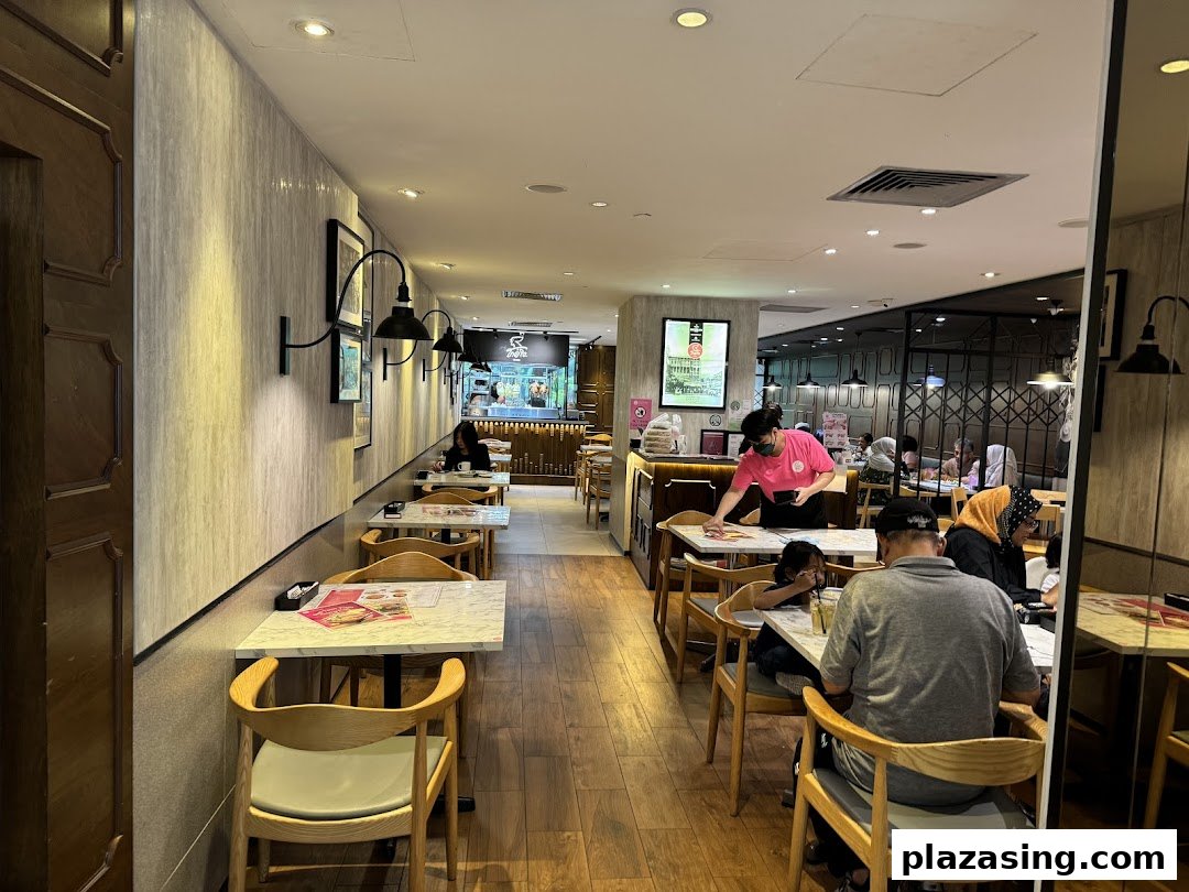 A view of the interior dining area at Go-Ang Pratunam Chicken Rice, with customers and staff present.