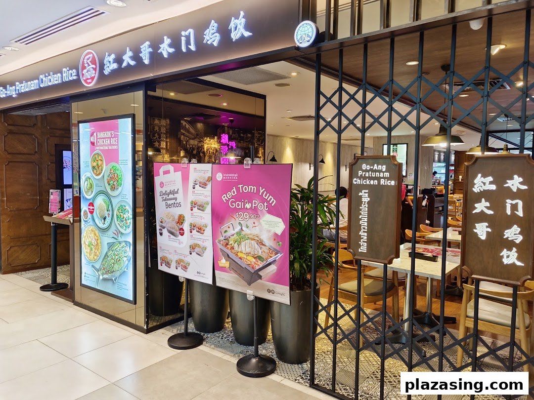 The storefront of Go-Ang Pratunam Chicken Rice, featuring promotional posters and a welcoming entrance.