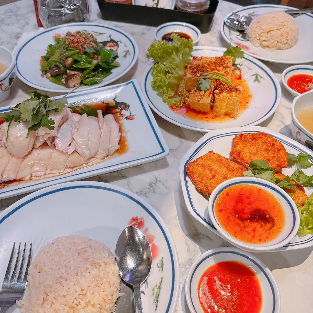 A table laden with various delicious Thai dishes, including sliced chicken, rice, vegetables, and fried items.