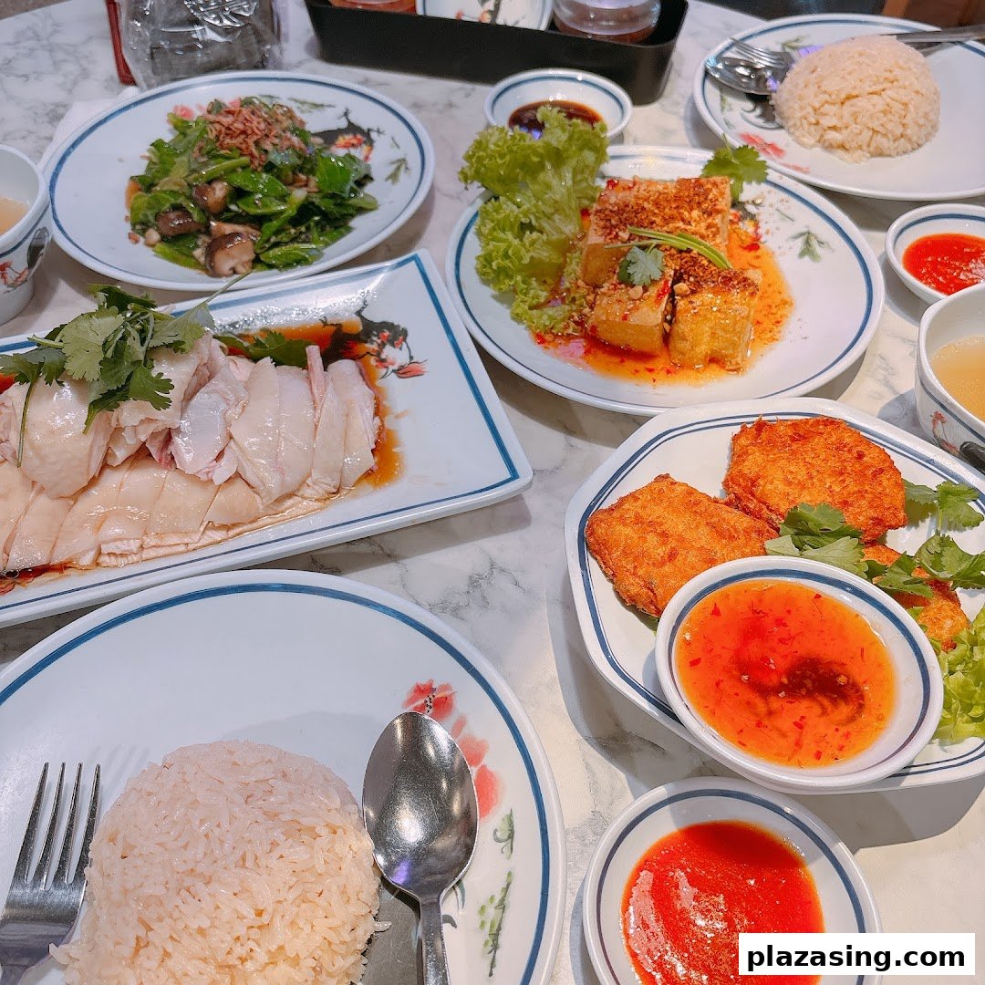 A table laden with various delicious Thai dishes, including sliced chicken, rice, vegetables, and fried items.
