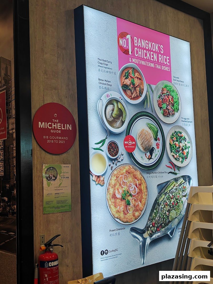 An illuminated display board showcasing Go-Ang Pratunam Chicken Rice's signature dishes and Michelin Bib Gourmand recognition.