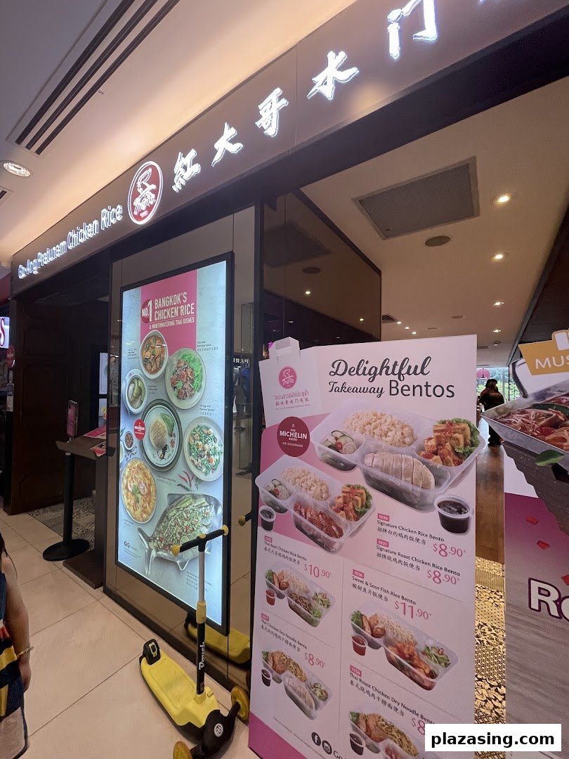 The illuminated entrance of Go-Ang Pratunam Chicken Rice, featuring a large display of takeaway bentos.