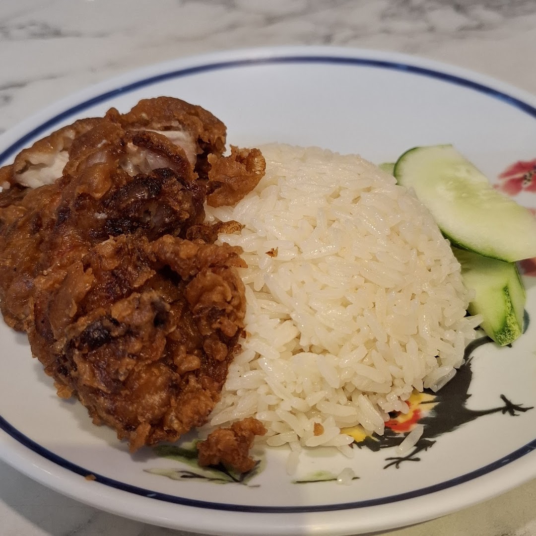 A plate of crispy fried chicken with fragrant rice and fresh cucumber slices.
