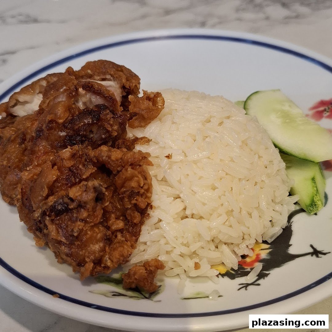 A plate of crispy fried chicken with fragrant rice and fresh cucumber slices.