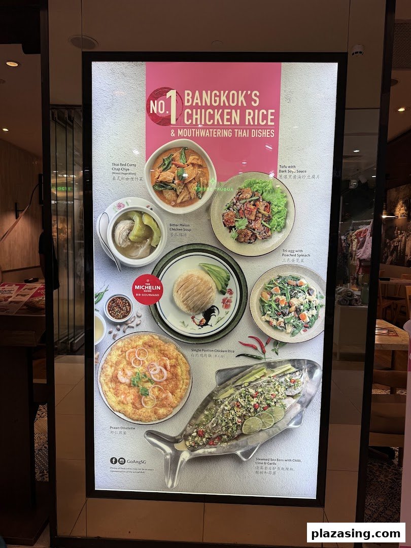 A brightly lit display board showcasing various Thai dishes, including chicken rice, curries, and seafood.