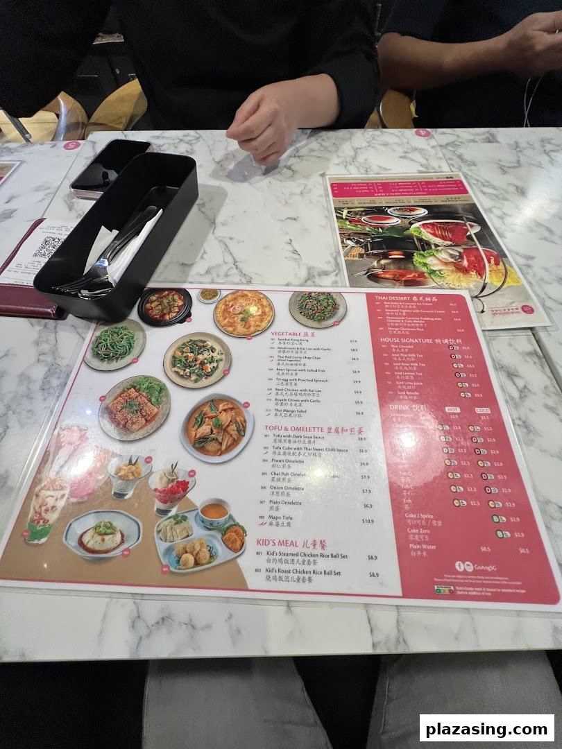 A detailed view of a restaurant menu displaying various Thai dishes, desserts, and drinks on a marble table.