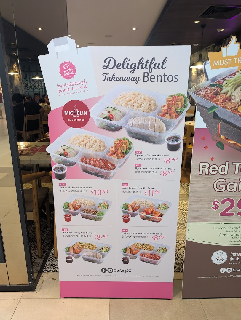 A promotional standee for Go-Ang Pratunam Chicken Rice, showcasing their takeaway bento sets.