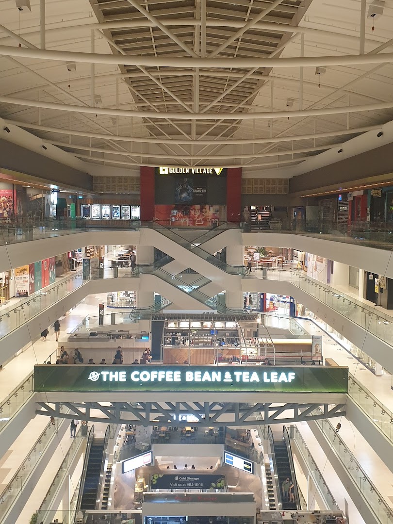 An expansive view of a multi-level shopping mall interior featuring various shops, escalators, and prominent brand signs.