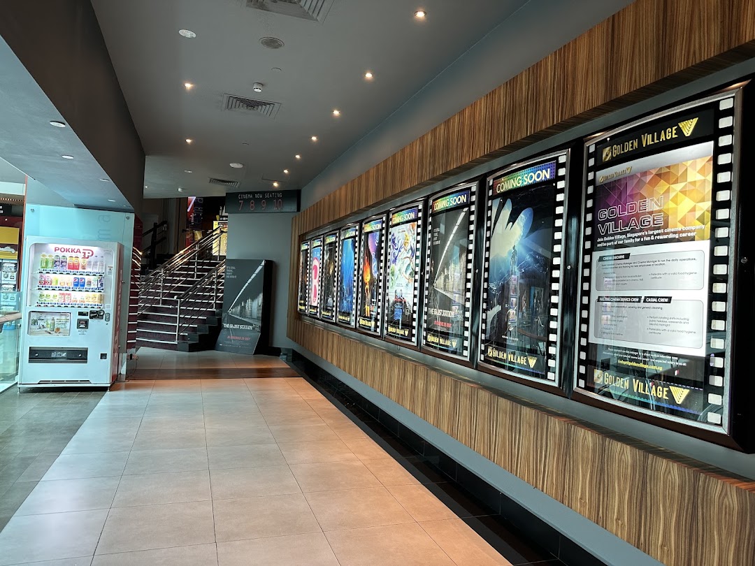 A bright cinema lobby featuring movie posters, a vending machine, and stairs to the cinema halls.