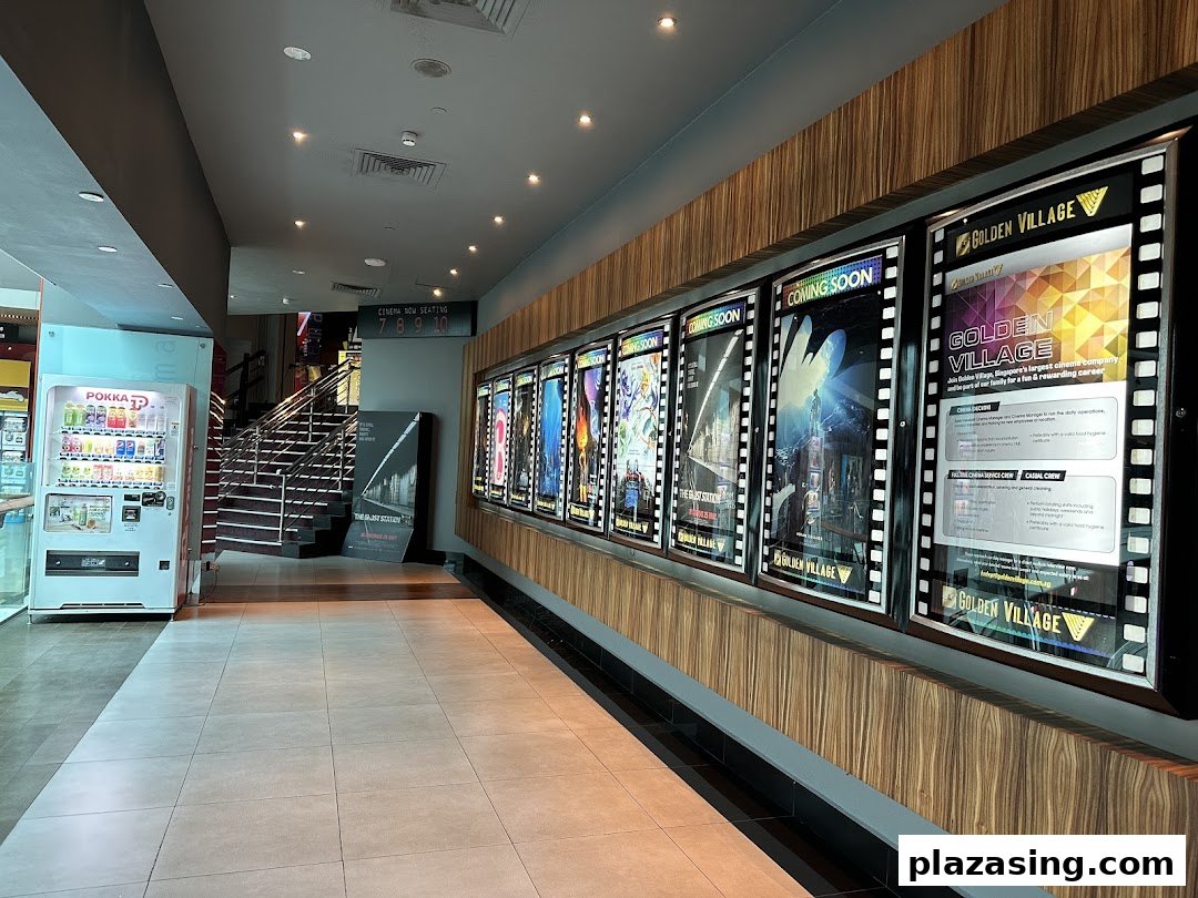 A bright cinema lobby featuring movie posters, a vending machine, and stairs to the cinema halls.