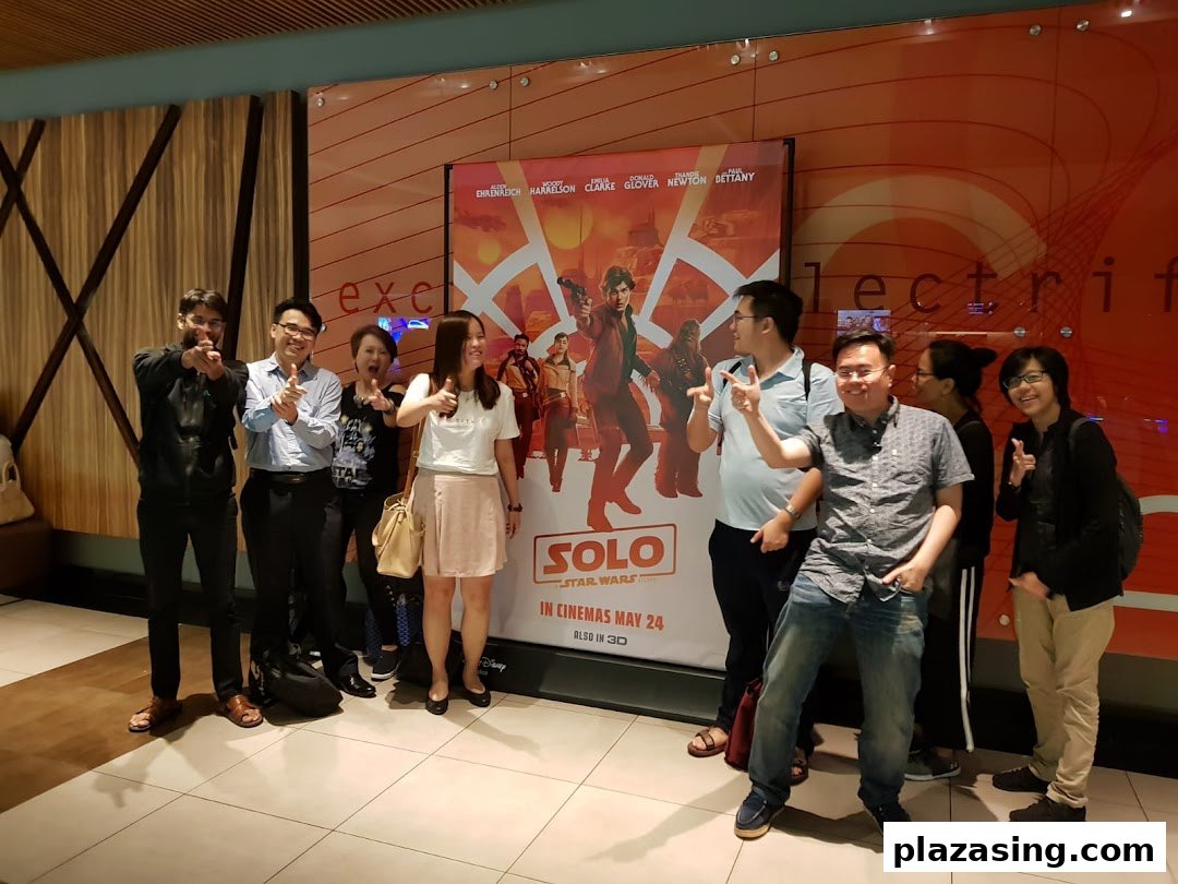 A group of friends posing happily in a cinema lobby next to a "Solo: A Star Wars Story" movie poster.