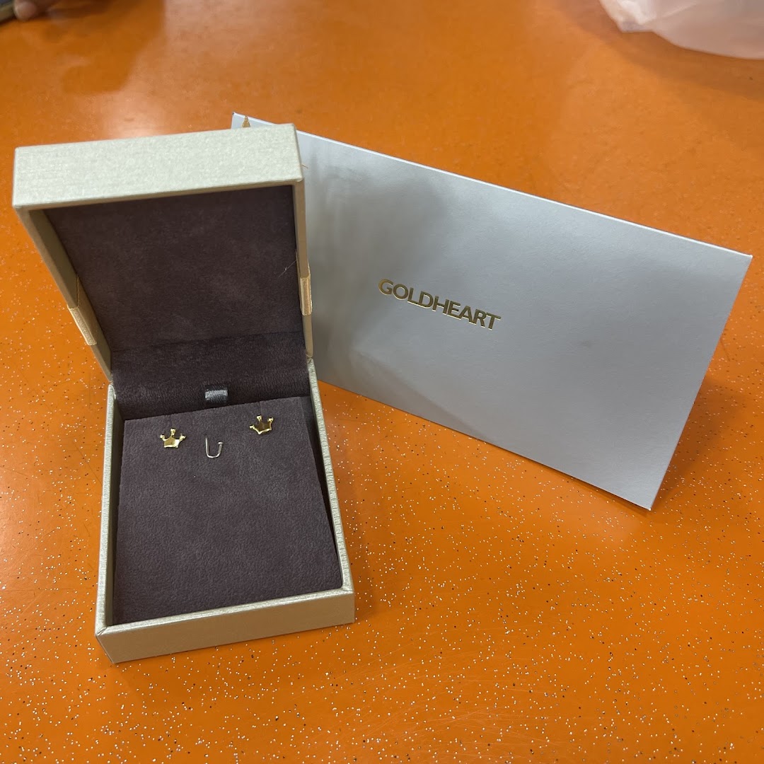 A pair of gold crown earrings displayed in an open Goldheart jewelry box with branded packaging.
