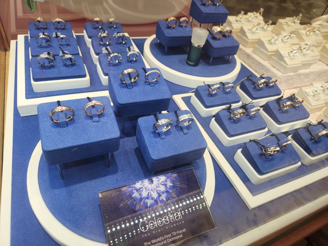 A display of various gold and diamond rings on blue velvet stands inside Goldheart Jewelry.