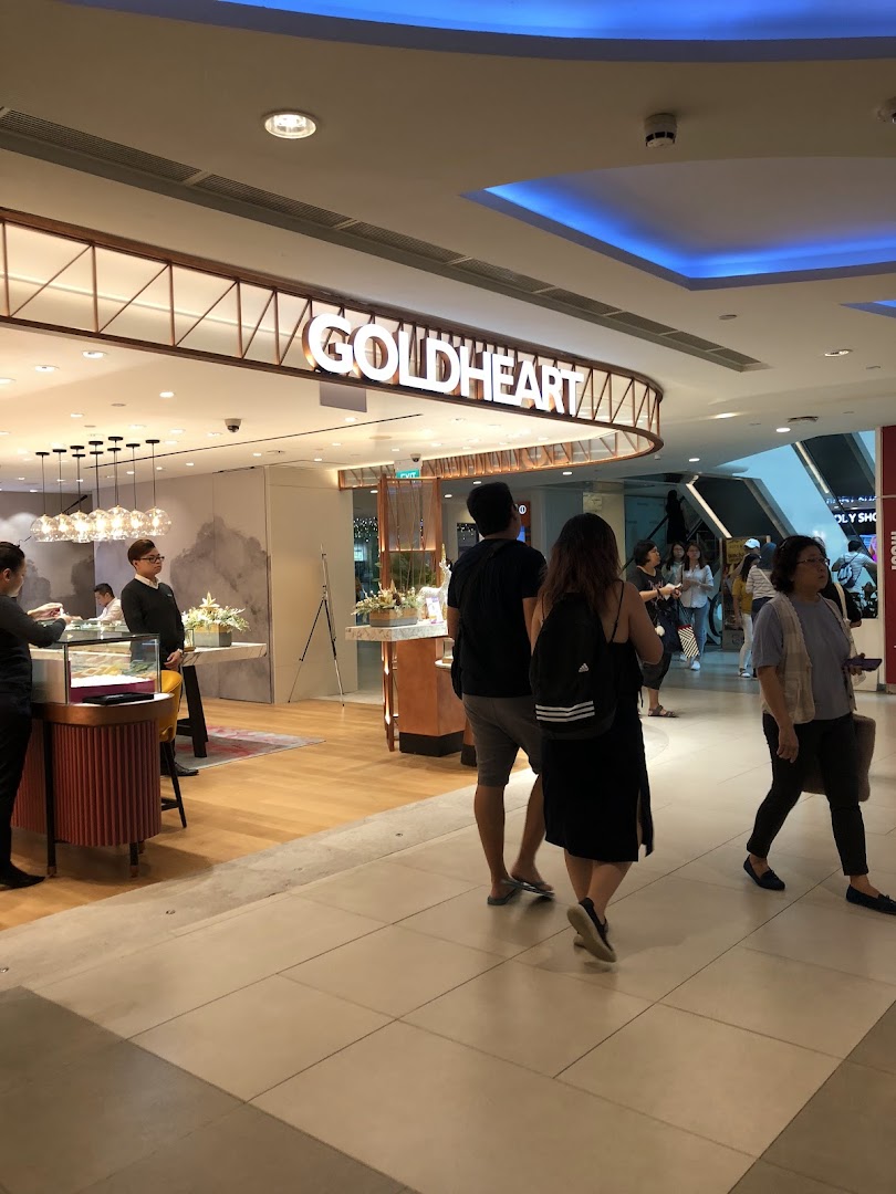 The Goldheart Jewelry shop entrance with its illuminated sign, showcasing elegant displays and shoppers passing by.