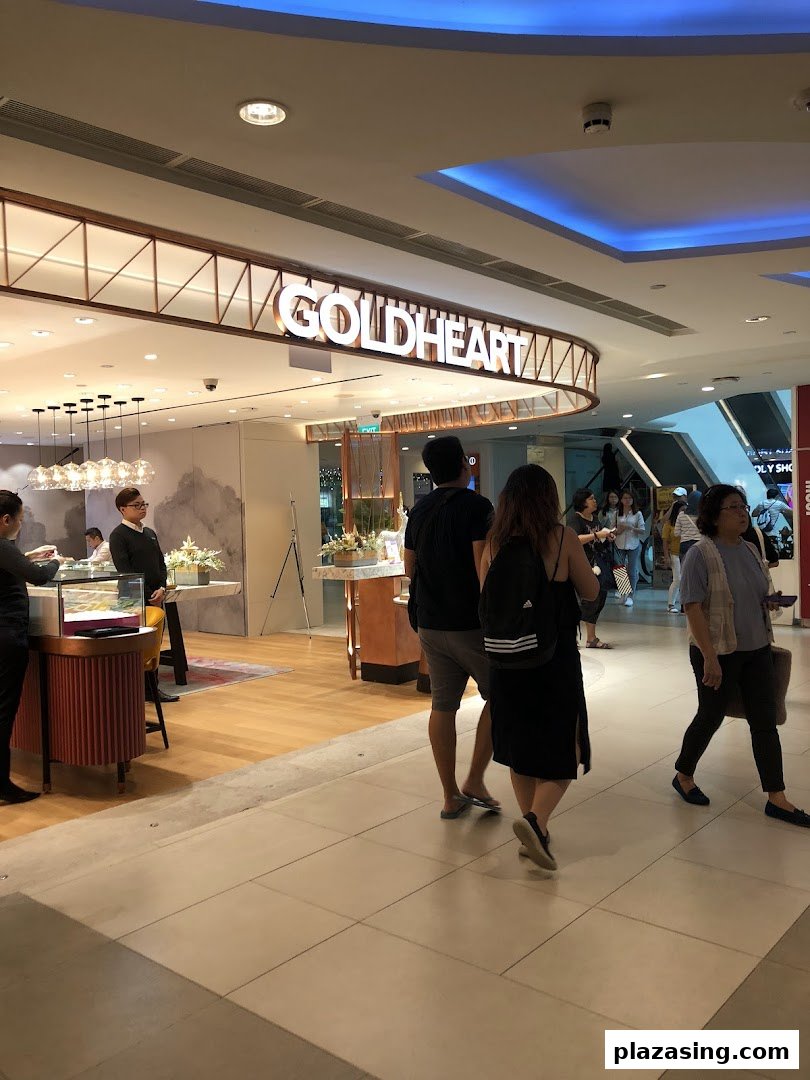 The Goldheart Jewelry shop entrance with its illuminated sign, showcasing elegant displays and shoppers passing by.