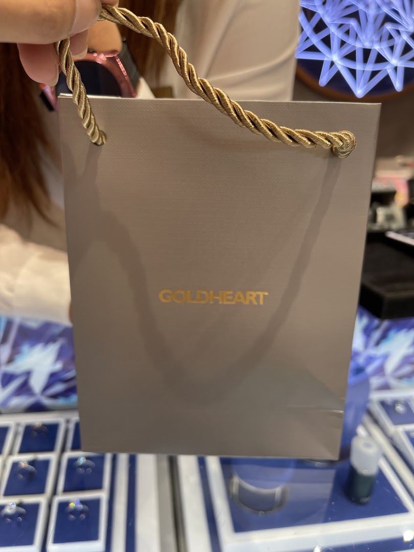 A person holds a Goldheart shopping bag inside the elegant jewelry store.