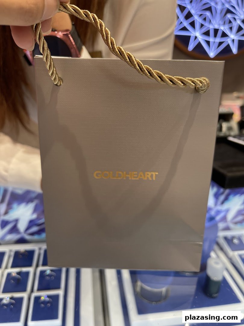 A person holds a Goldheart shopping bag inside the elegant jewelry store.