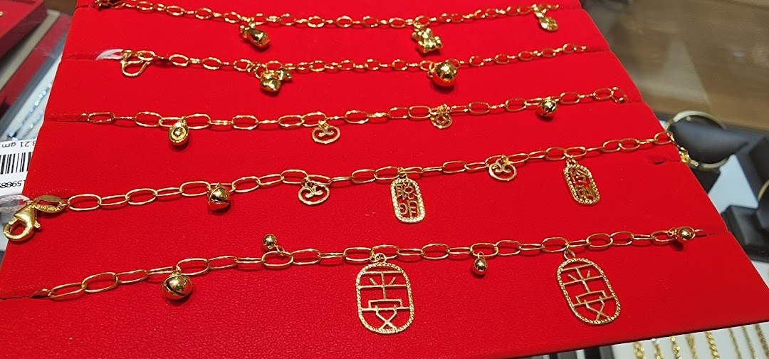 Close-up of several gold charm bracelets displayed on a red velvet stand.
