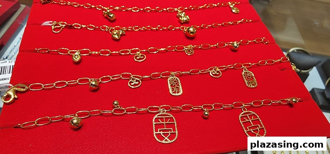 Close-up of several gold charm bracelets displayed on a red velvet stand.