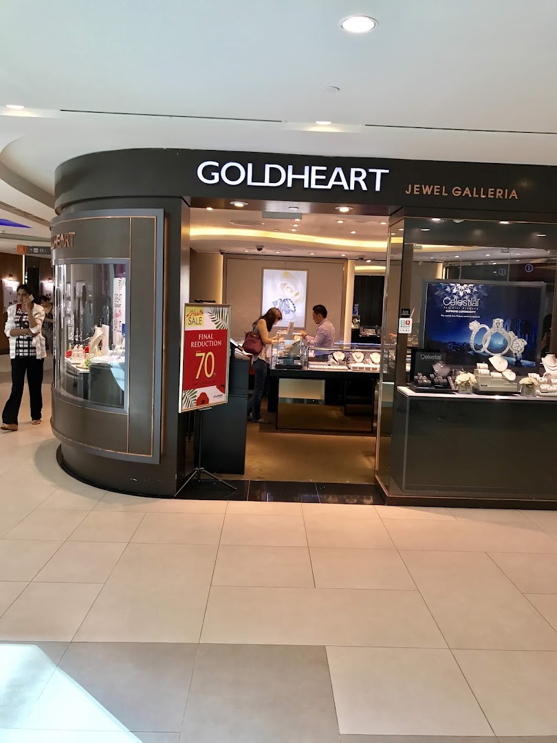 The shop front of Goldheart Jewelry, featuring display cases, a sale sign, and customers browsing.