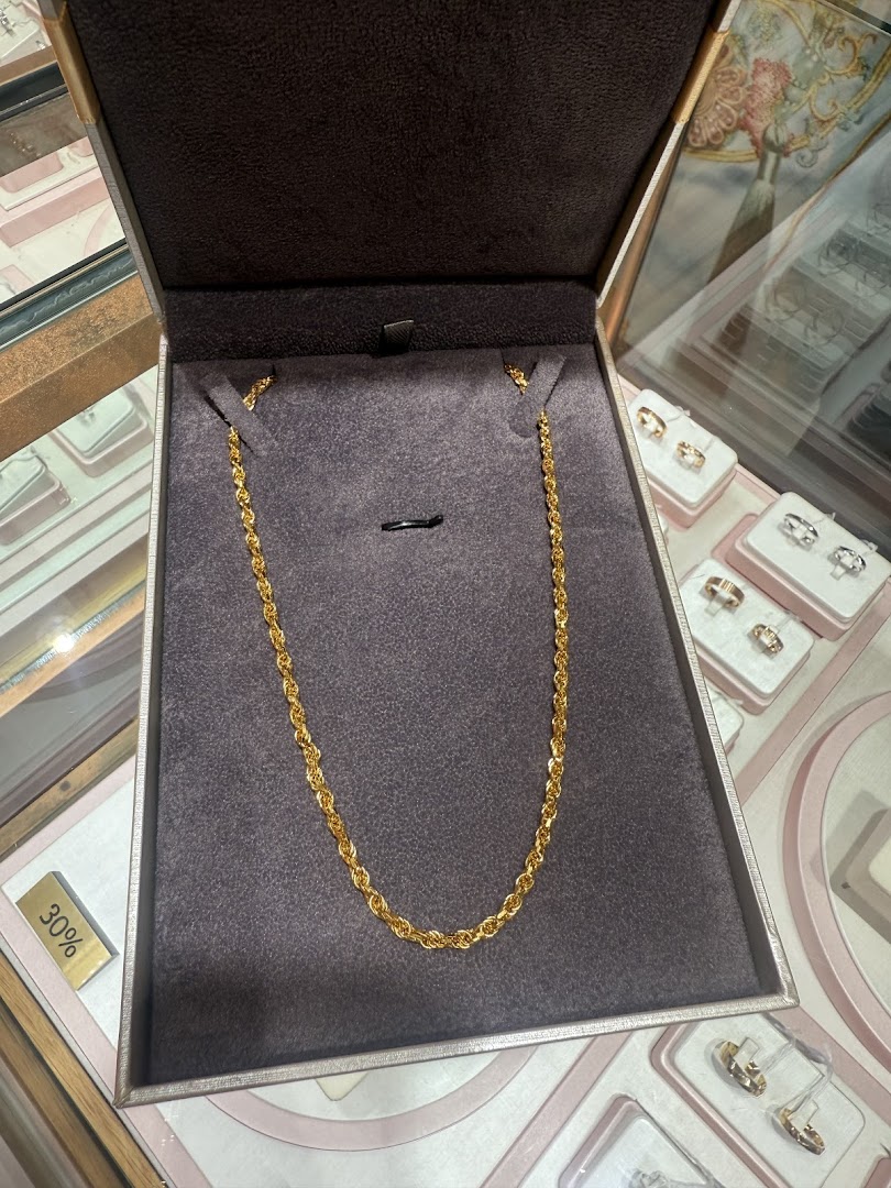 A gleaming gold chain displayed in a box, surrounded by other exquisite jewelry pieces.