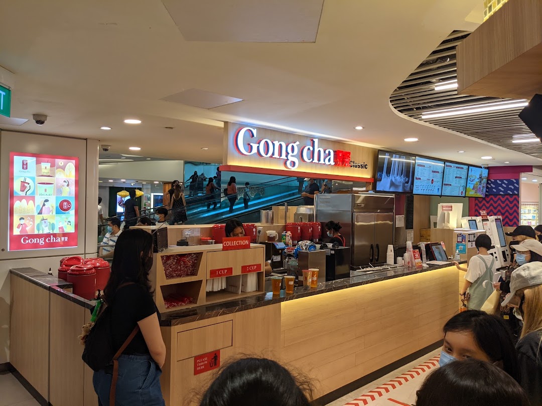 Customers queueing at the vibrant Gong Cha counter, featuring digital menus and a bustling atmosphere.