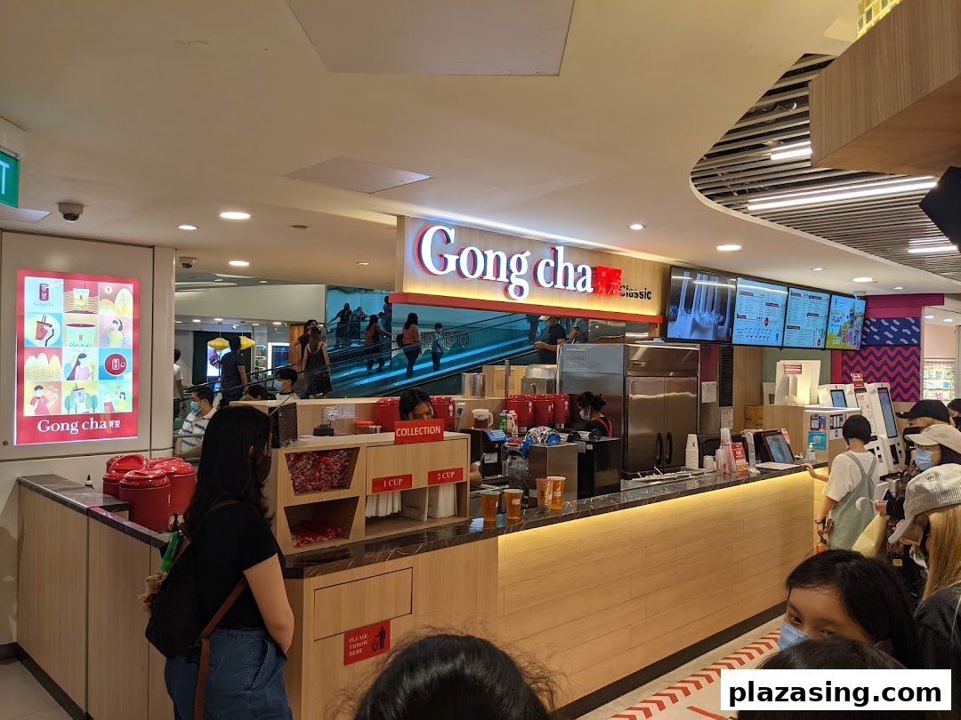 Customers queueing at the vibrant Gong Cha counter, featuring digital menus and a bustling atmosphere.