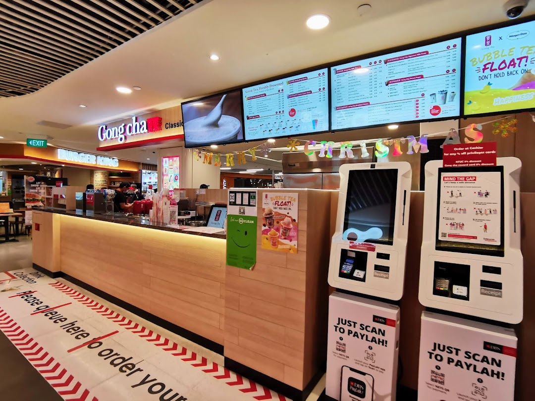 Gong Cha counter with digital menu boards displaying various bubble tea options and self-order kiosks.