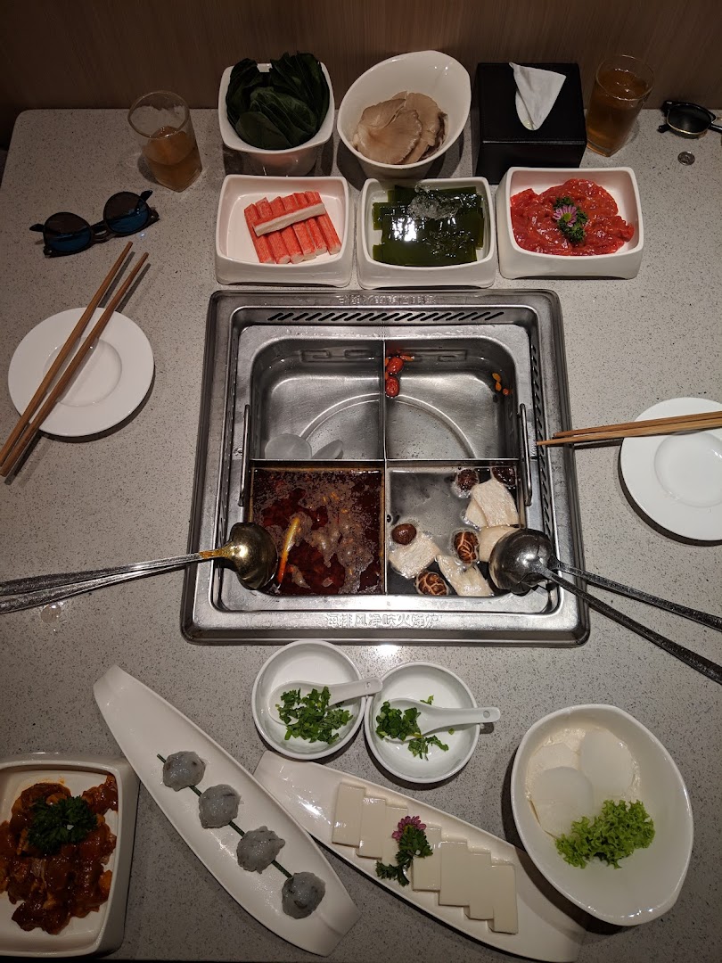 A vibrant hotpot spread featuring fresh ingredients, broths, and condiments ready for cooking.