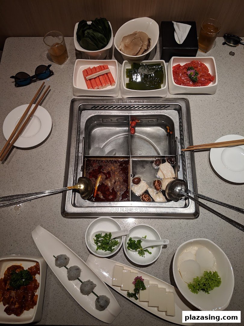 A vibrant hotpot spread featuring fresh ingredients, broths, and condiments ready for cooking.