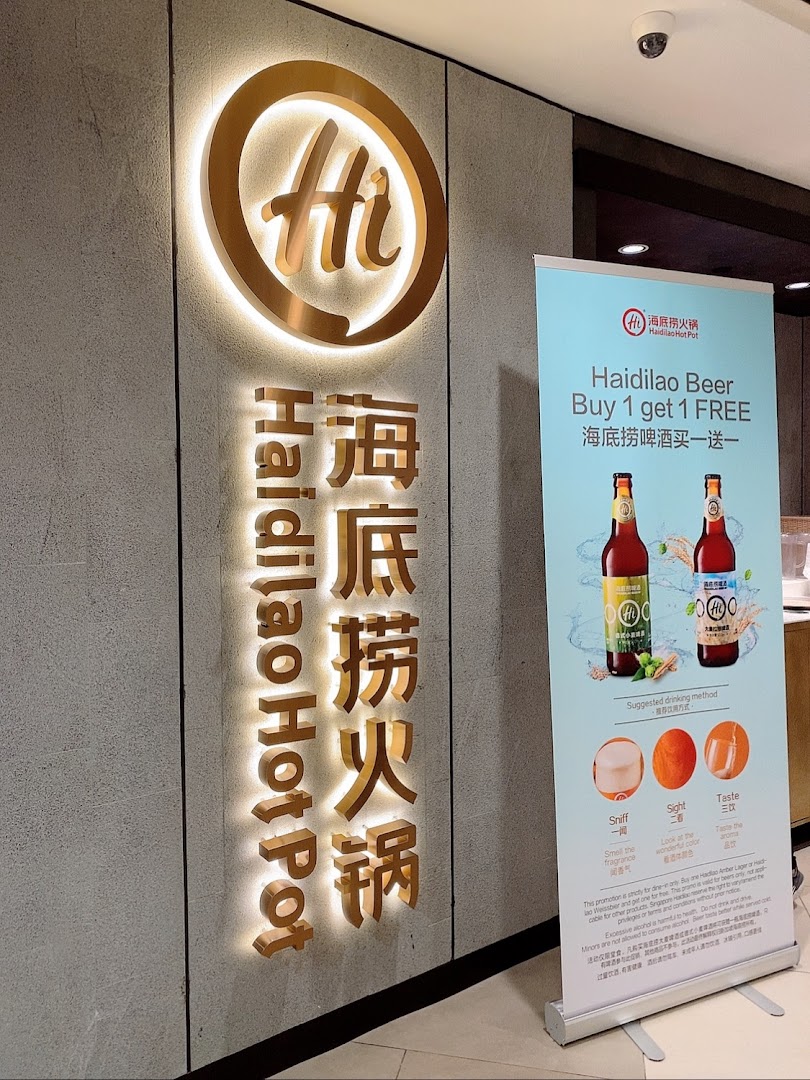Illuminated Haidilao Hot Pot sign at shop entrance with a promotional banner.