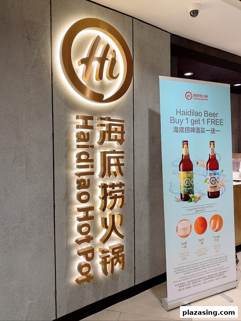 Illuminated Haidilao Hot Pot sign at shop entrance with a promotional banner.