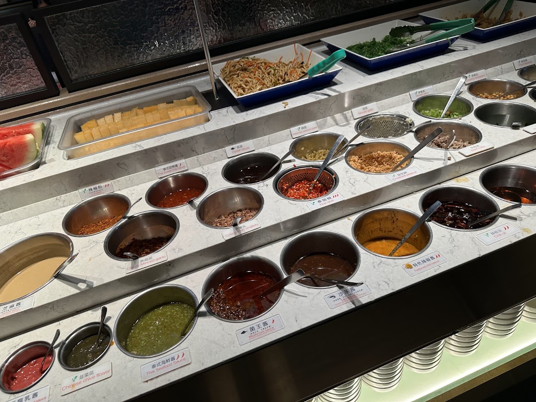 A vibrant self-service condiment and sauce bar at Haidilao Hot Pot, featuring various ingredients for custom dipping sauces.