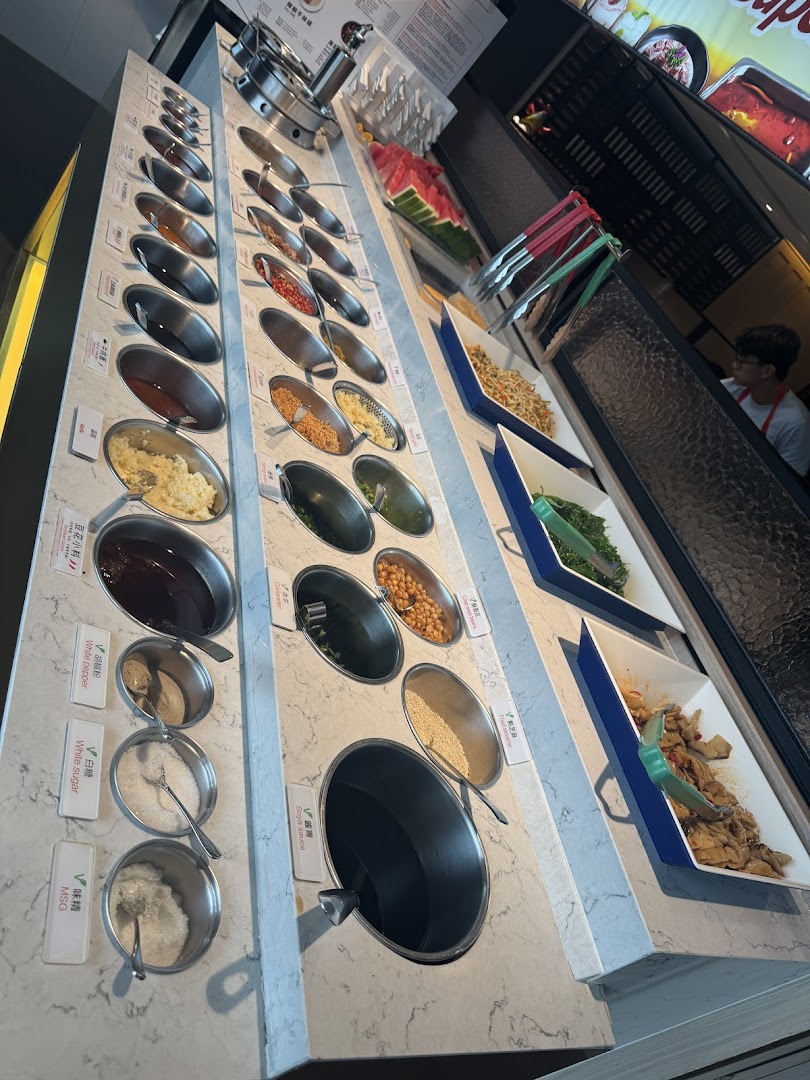 A vibrant self-service condiment and side dish bar at Haidilao Hot Pot, featuring various sauces and fresh ingredients.