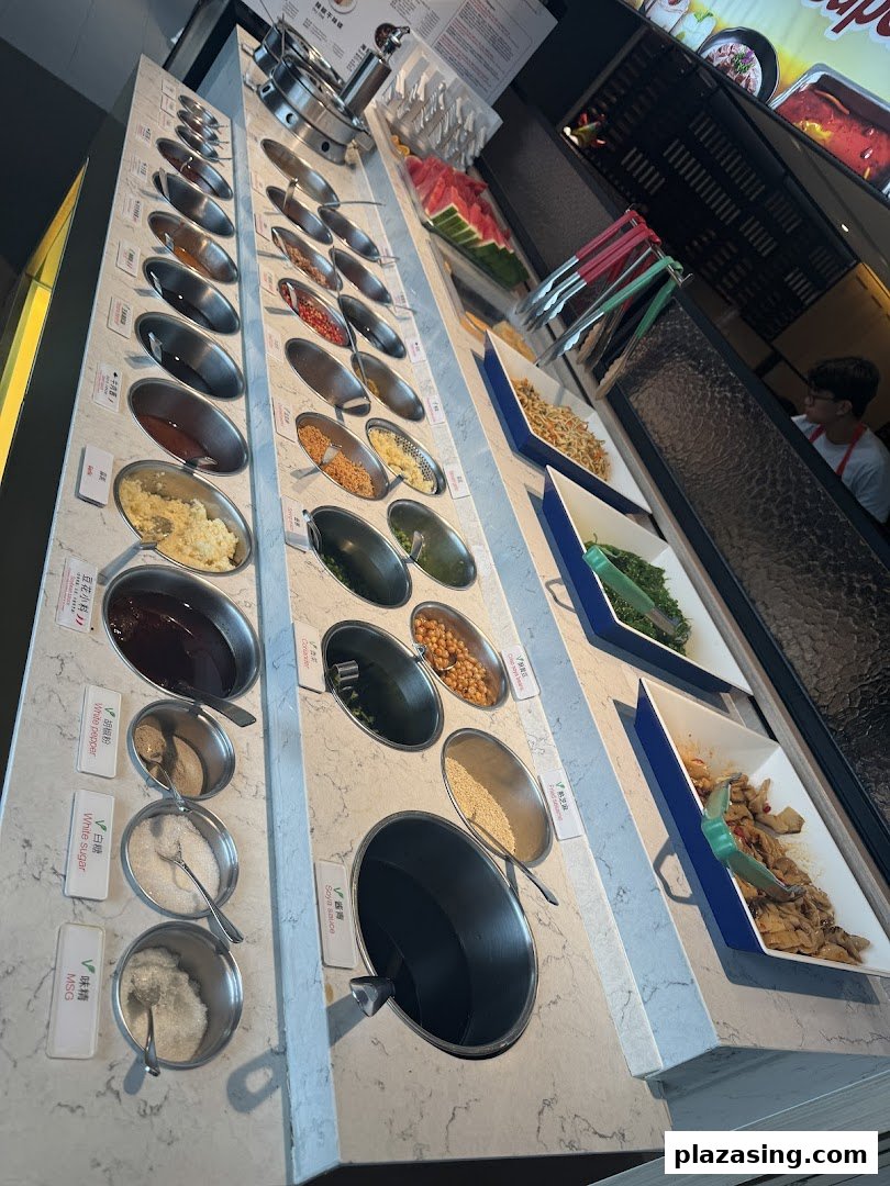 A vibrant self-service condiment and side dish bar at Haidilao Hot Pot, featuring various sauces and fresh ingredients.