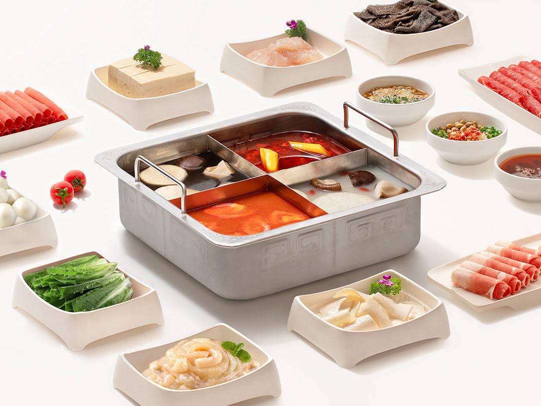 A vibrant hot pot spread featuring a multi-compartment pot and various fresh ingredients.