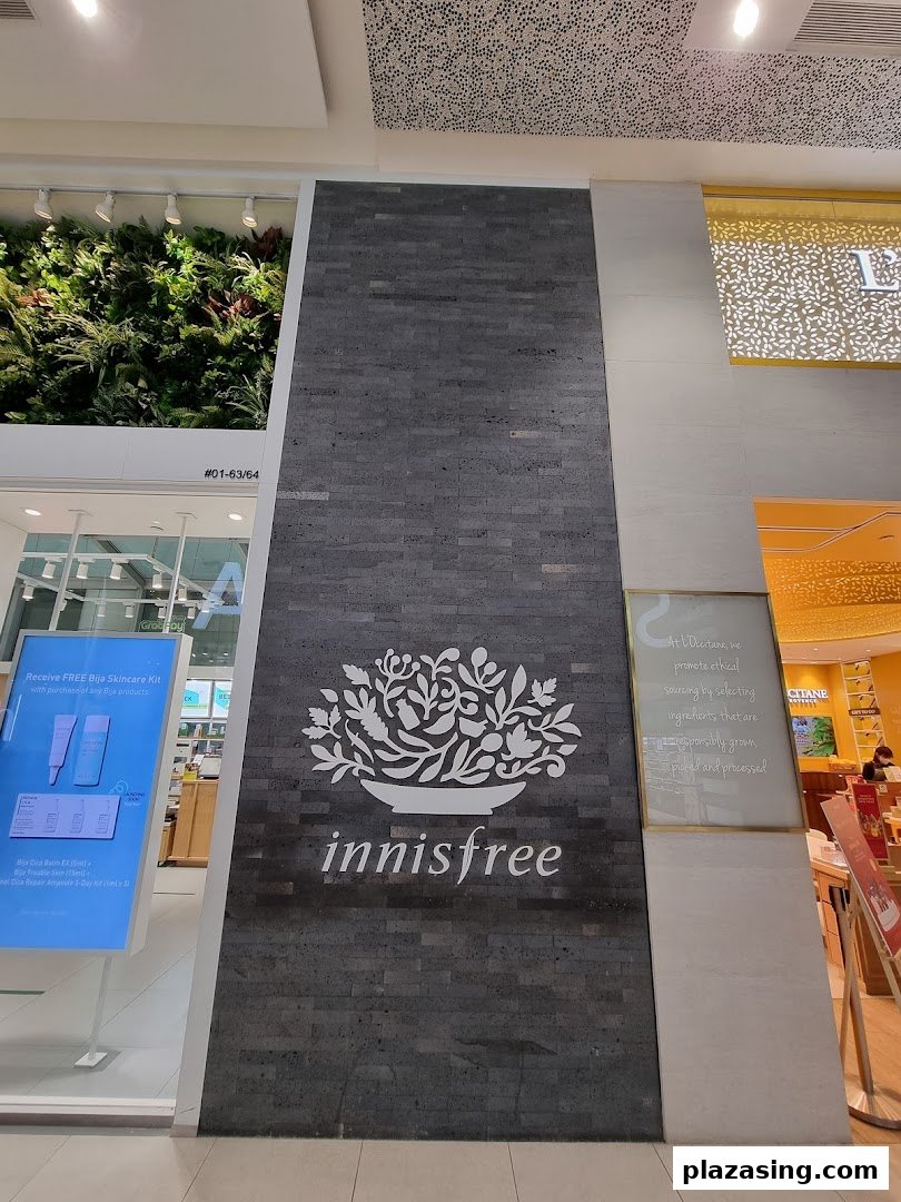The innisfree shopfront at Plaza Singapura, featuring its distinctive logo and a lush green wall.