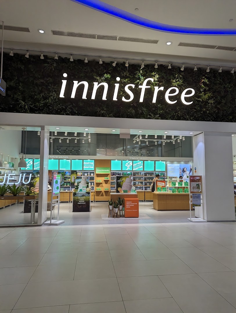 The innisfree shop entrance features a green wall with its logo, showcasing a bright, natural-themed interior.