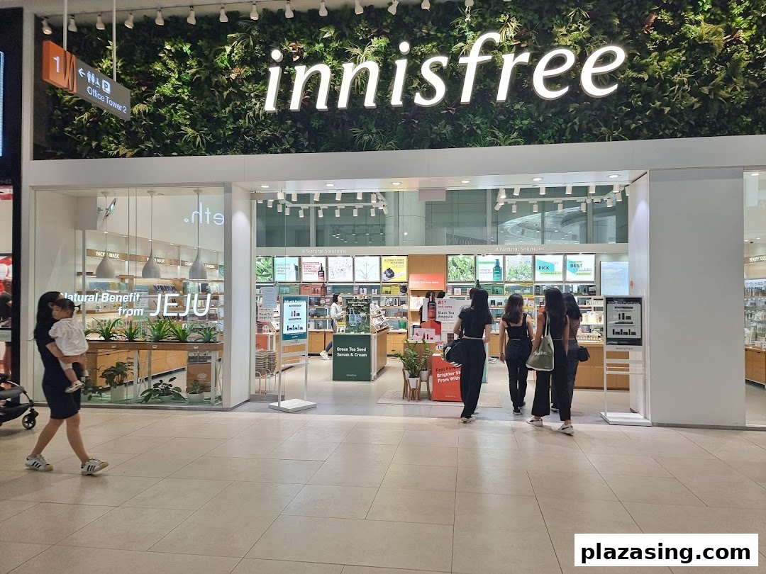 The innisfree shop entrance featuring a lush green wall with the brand logo and customers entering.