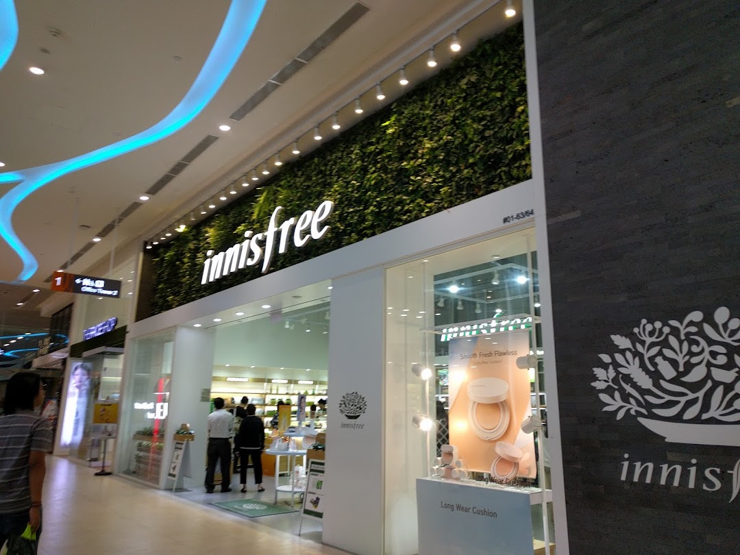 The innisfree shopfront at Plaza Singapura, featuring a green wall and bright interior.