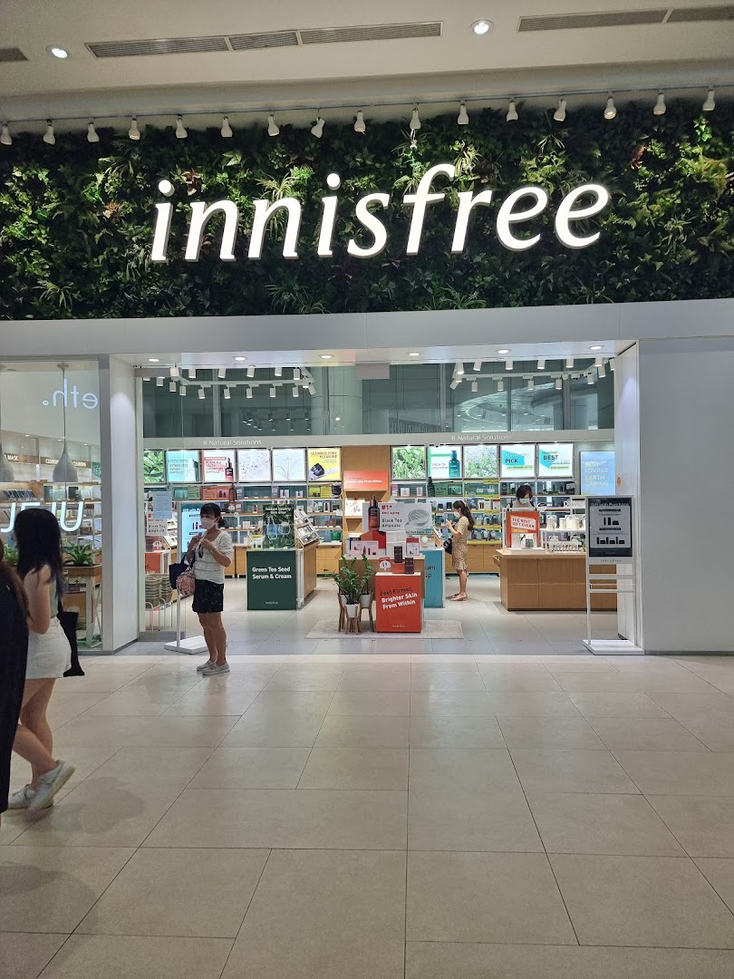 Innisfree shop entrance featuring its signature green wall logo and visible skincare product displays.