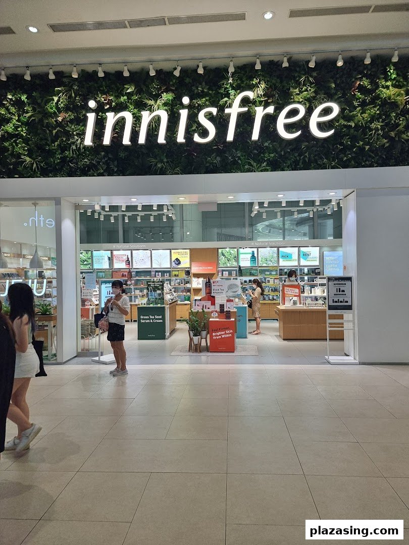 Innisfree shop entrance featuring its signature green wall logo and visible skincare product displays.
